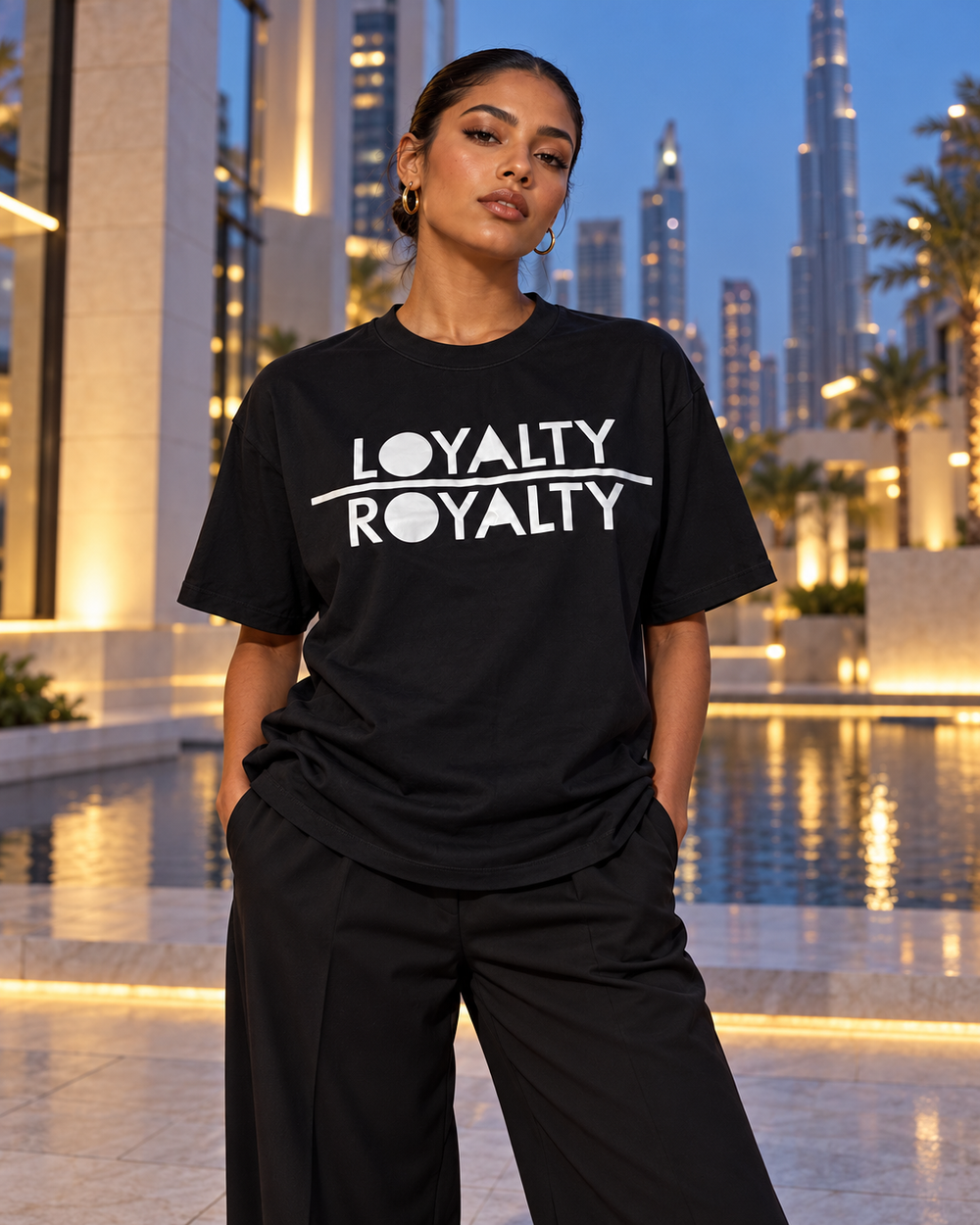 Black Loyalty Over Royalty shirt styled against a city skyline at dusk